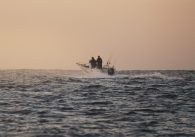 Offshore fishing boat cruising in the Pacific Ocean at sunset