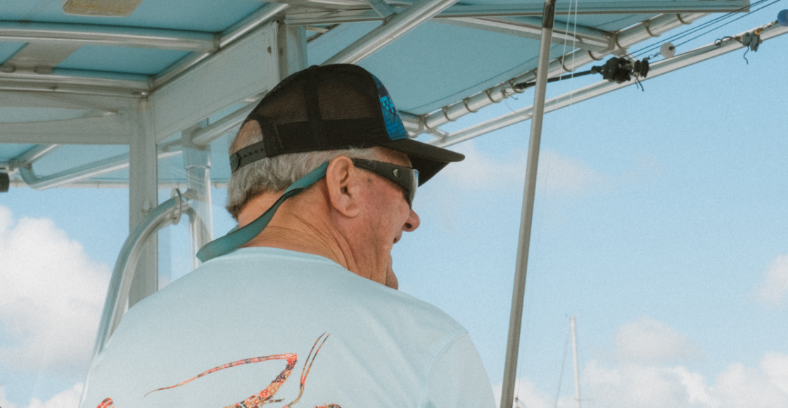 A captain smiles while looking out over the water from the helm of his powerboat.