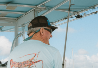 A captain smiles while looking out over the water from the helm of his powerboat.