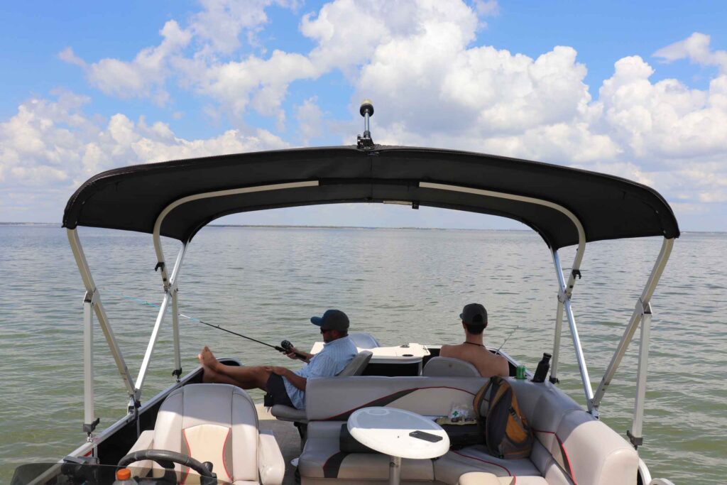 Two men fishing from the back of a pontoon on Lake Lewisville, Texas